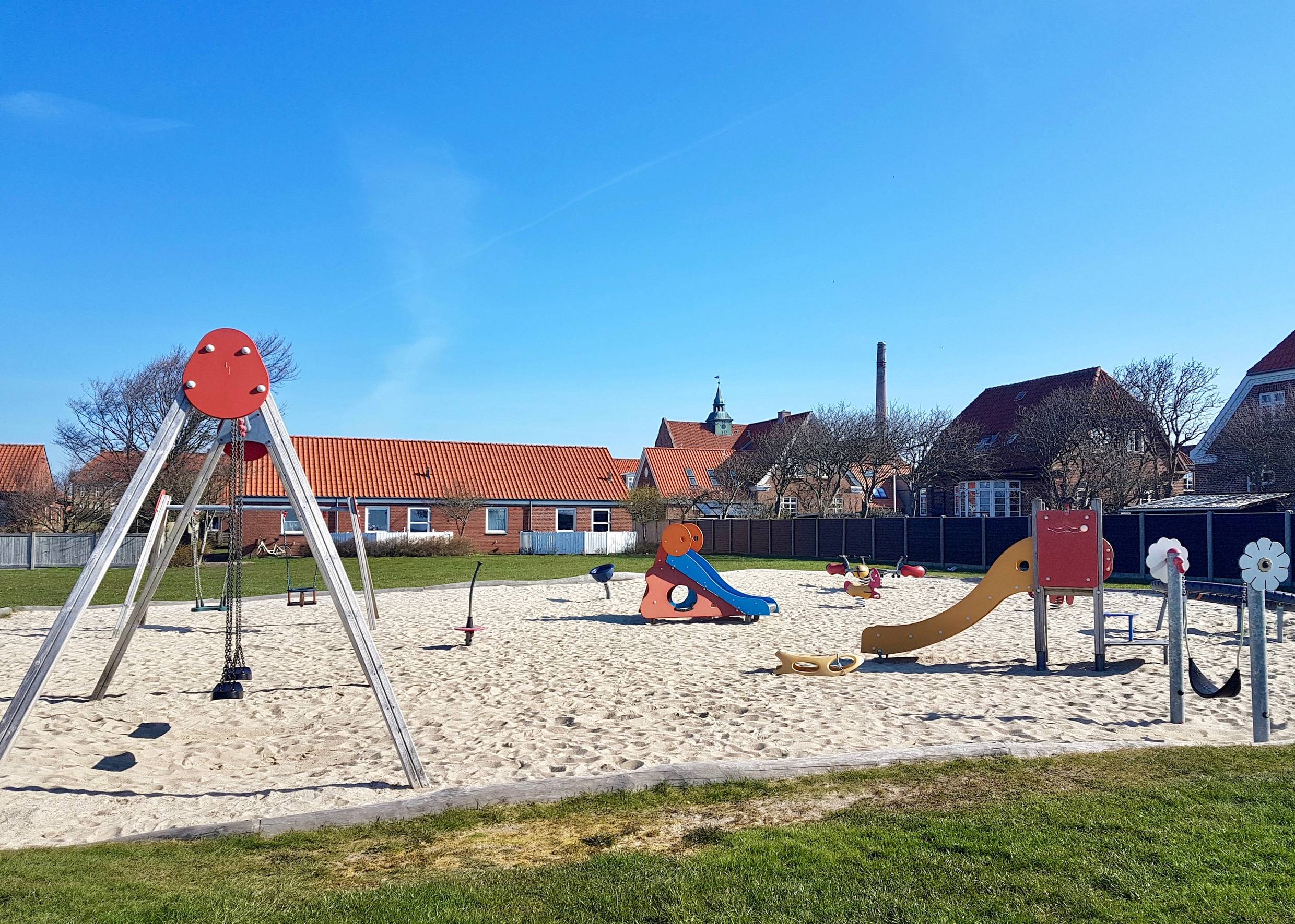 Spielplatz auf einer Wiese zwischen Backsteinhäusern