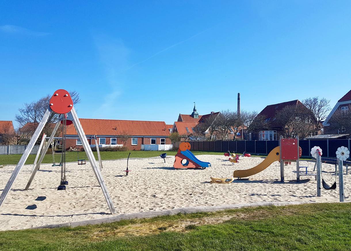 Spielplatz auf einer Wiese zwischen Backsteinhäusern