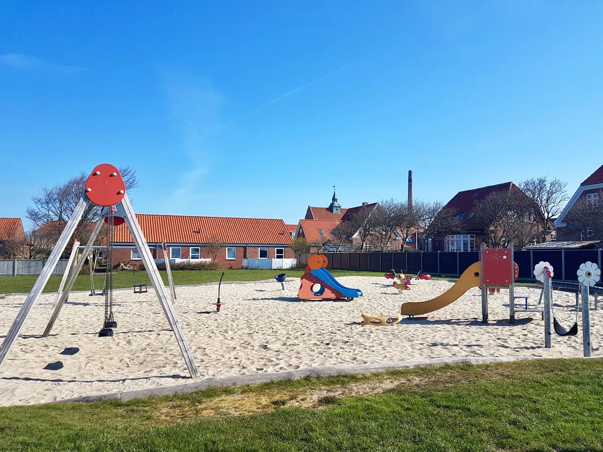 Spielplatz auf einer Wiese zwischen Backsteinhäusern
