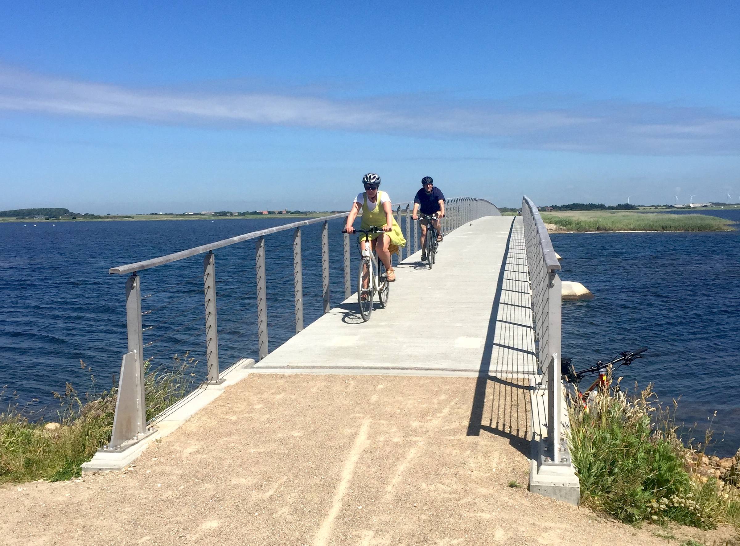 Schmale Brücke mit Radfahrern über einen See