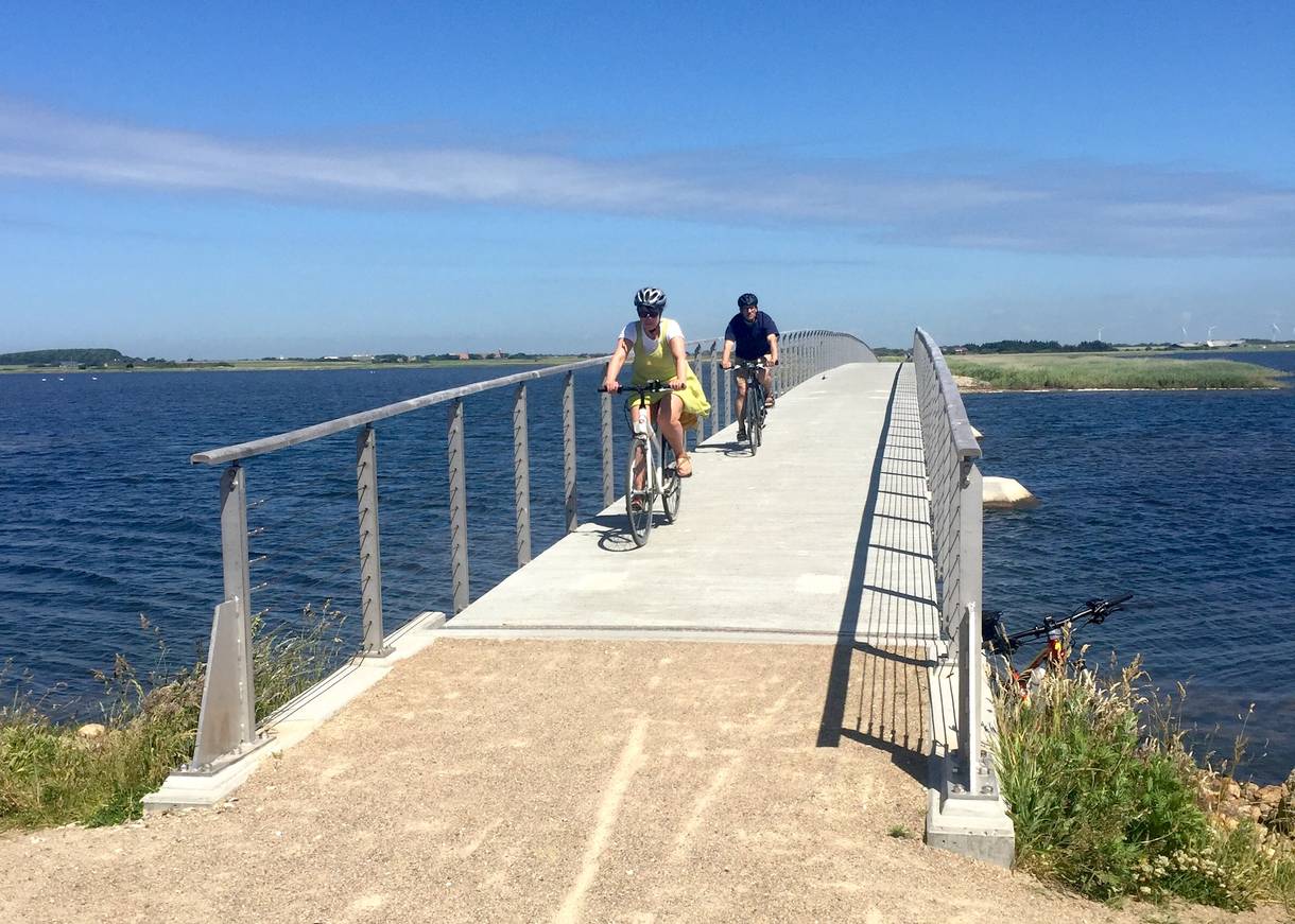 Schmale Brücke mit Radfahrern über einen See