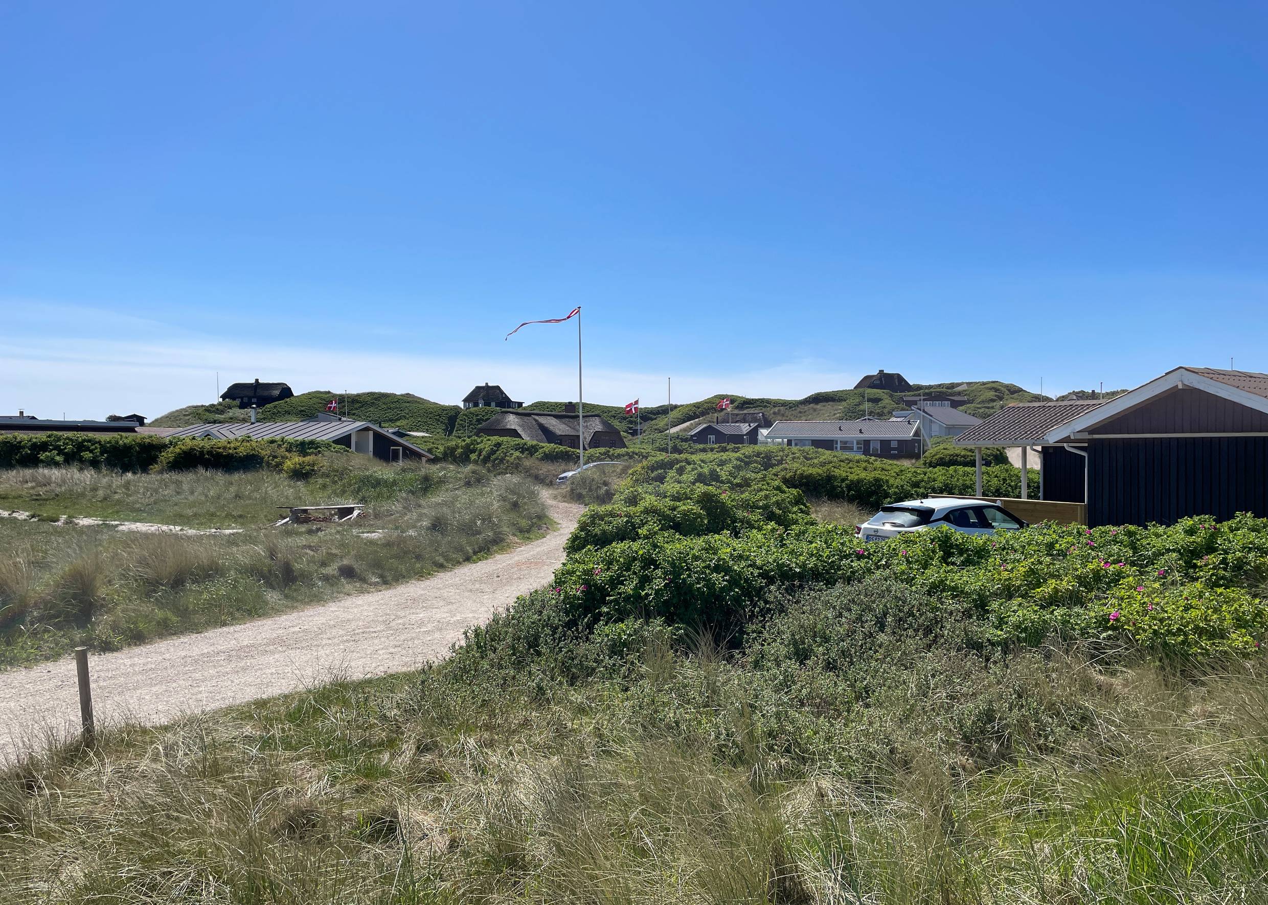 Kleiner Schotterweg mit Ferienhäuser rechts und links in den Dünen versteckt