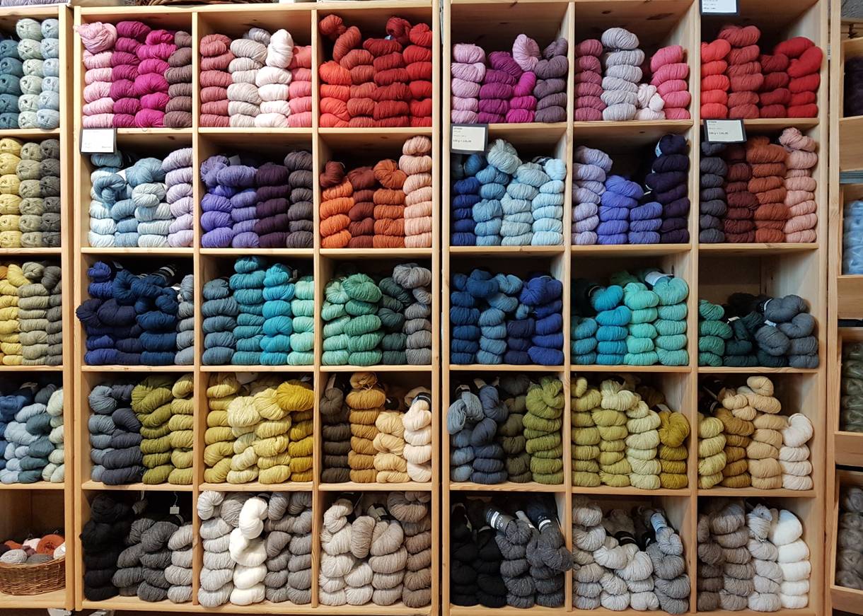 Blick auf ein Regal mit farblich sortieren Handstrickgarnen