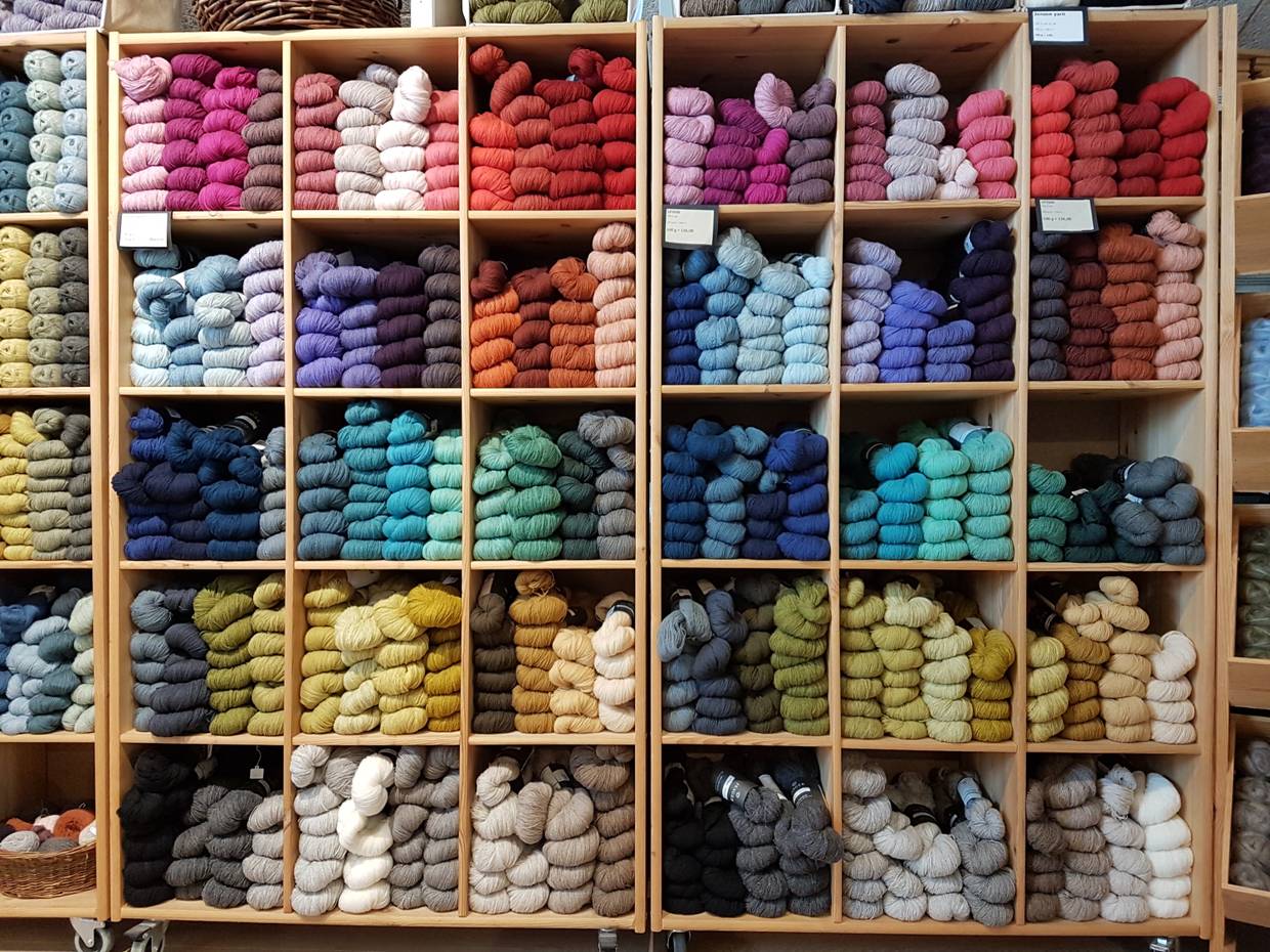 Blick auf ein Regal mit farblich sortieren Handstrickgarnen
