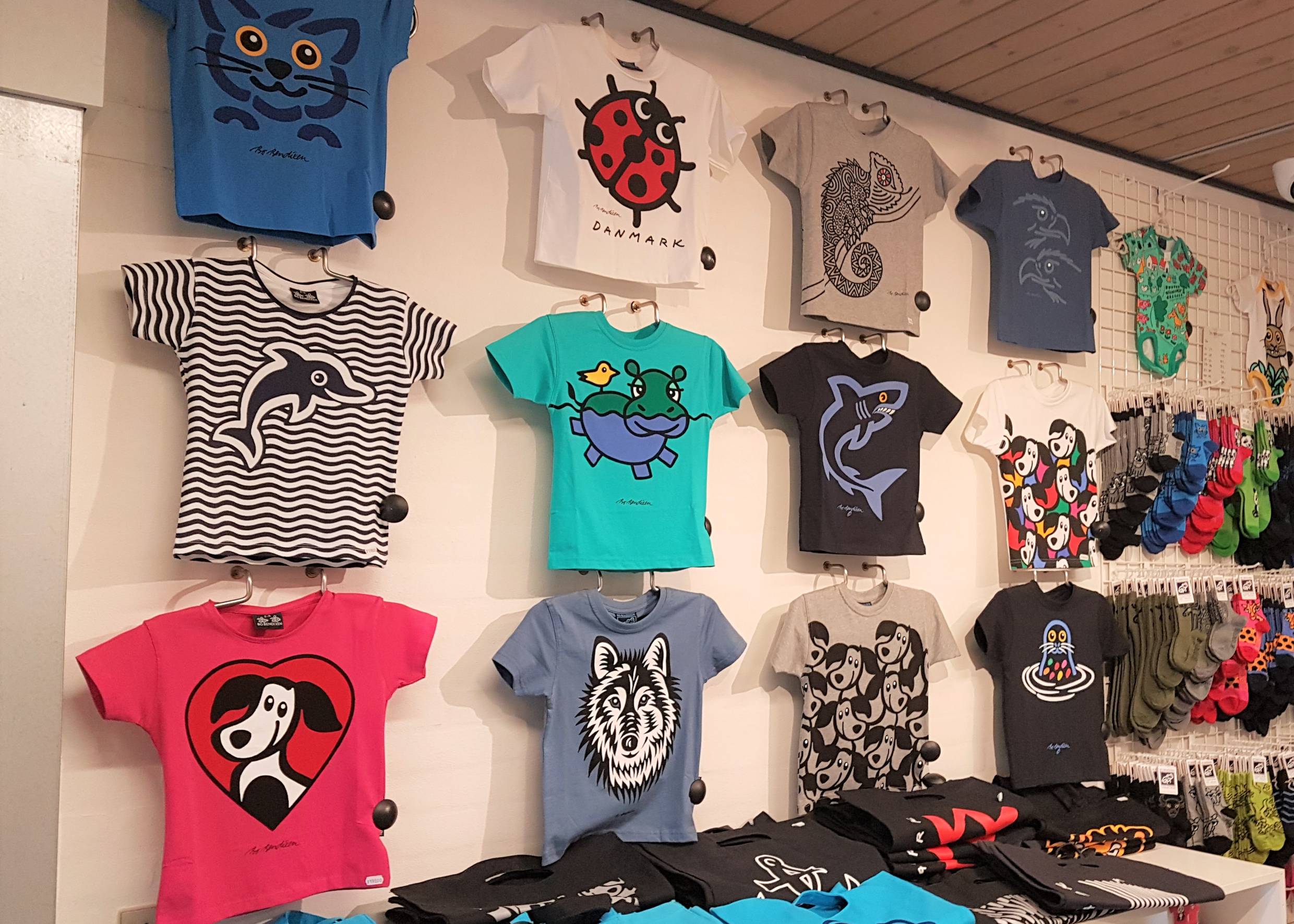 Eine Wand mit bunten T-Shirts von Bo Bendixen