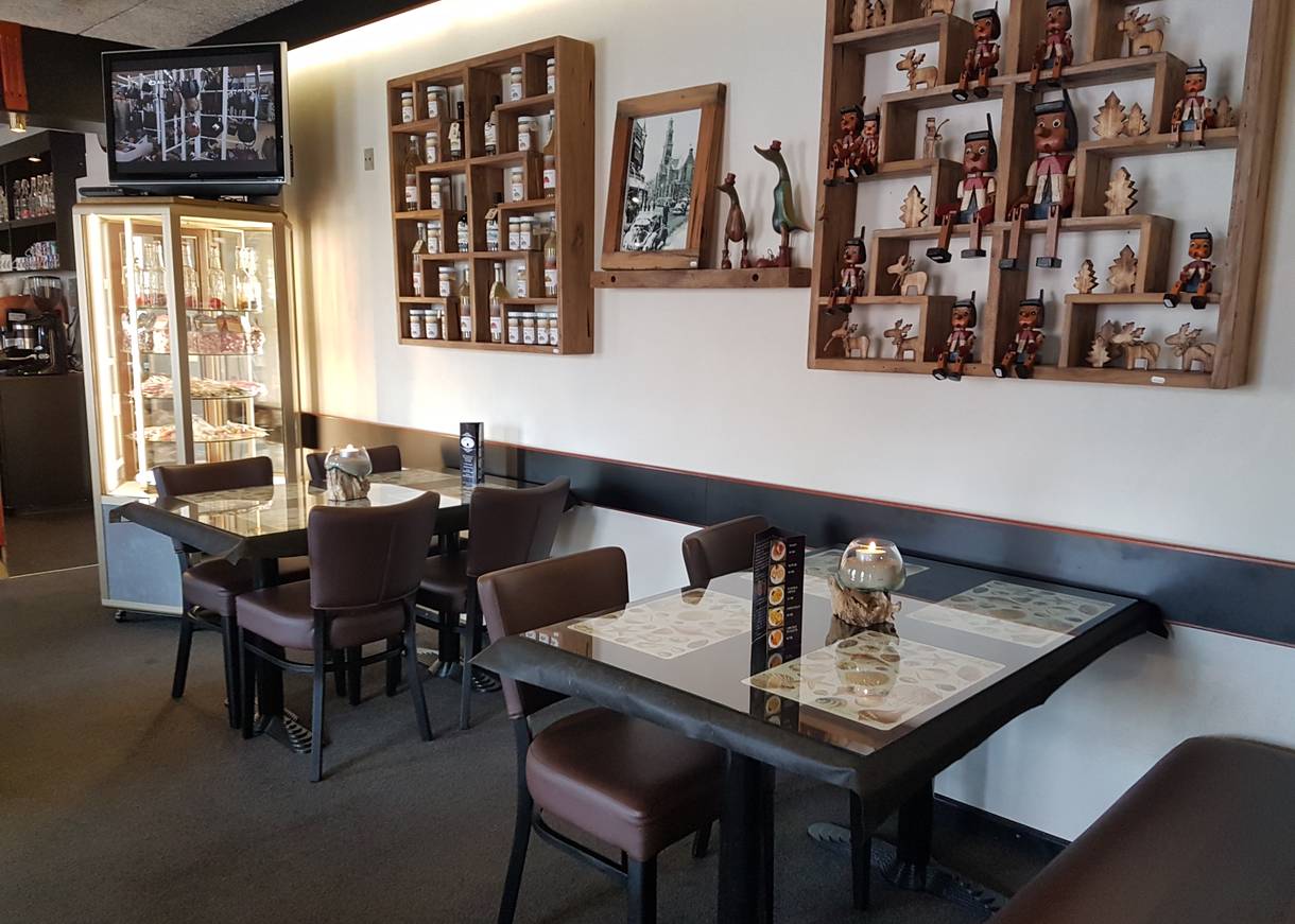 Zwei Tische im Café, darüber Regale mit Holzfiguten und Marmelade