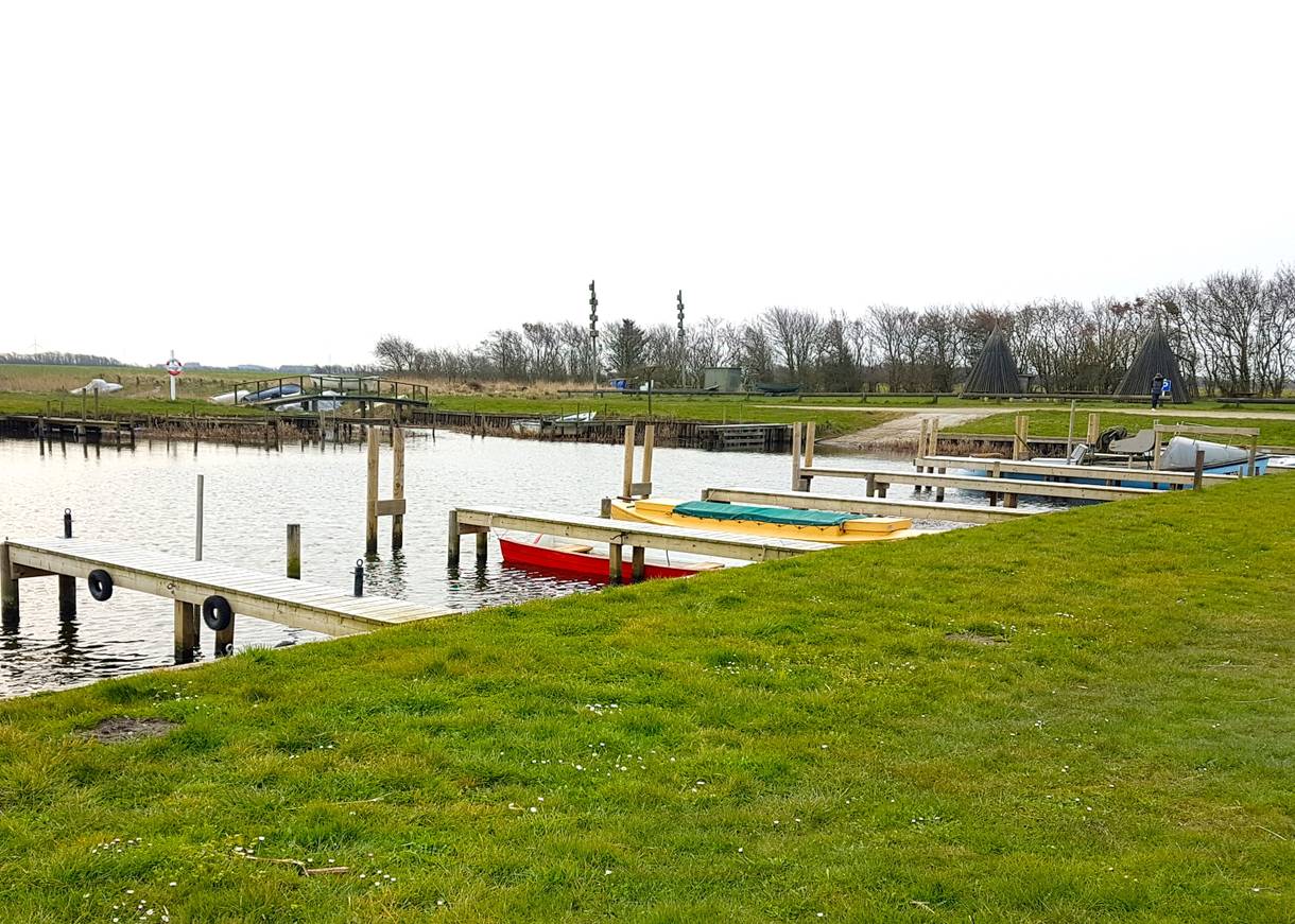 Kleiner Hafen mit bunten Booten und Bänken am Ufer