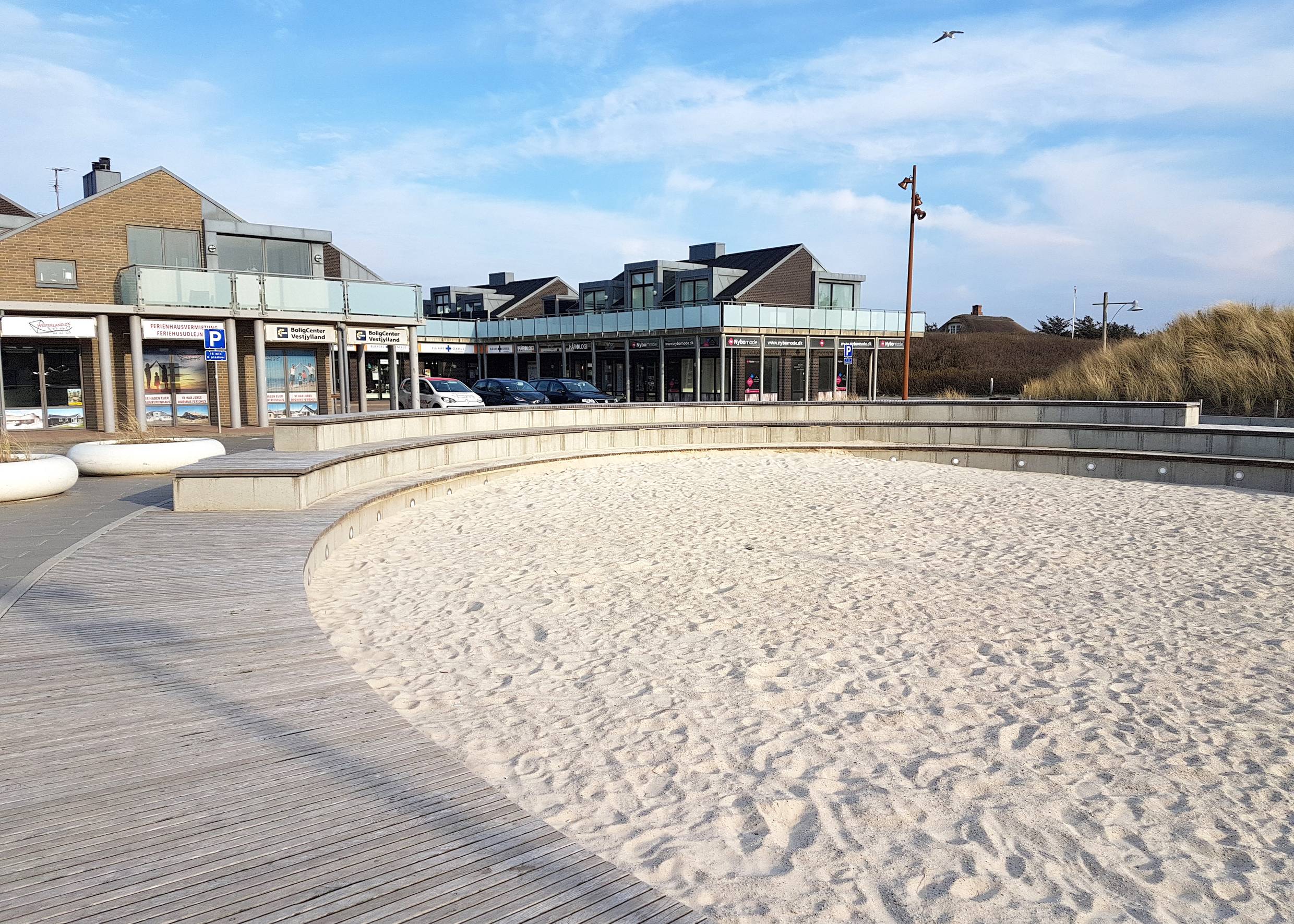 Runder Sandkasten, dahinter Geschäfte