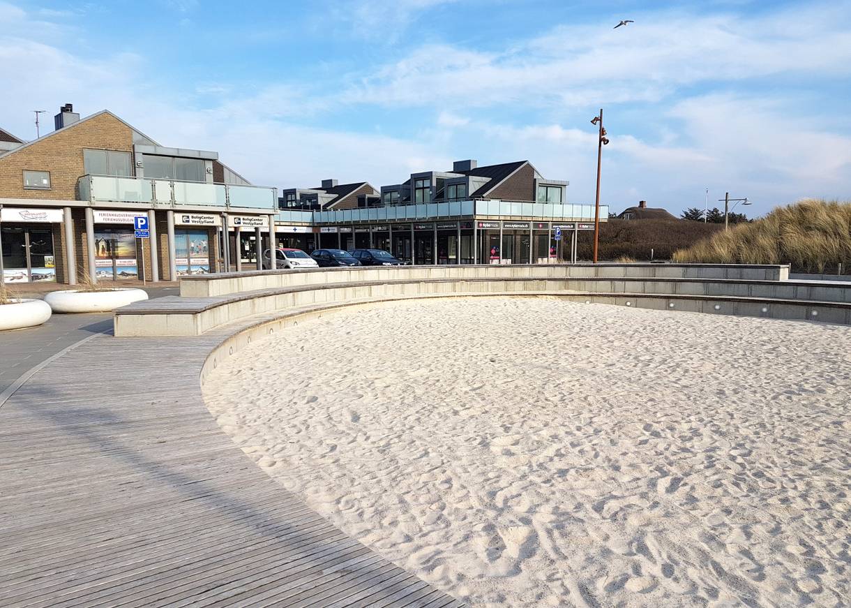 Runder Sandkasten, dahinter Geschäfte