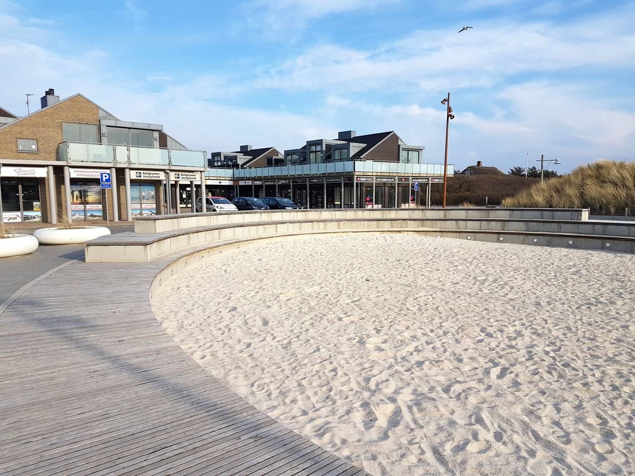 Runder Sandkasten, dahinter Geschäfte