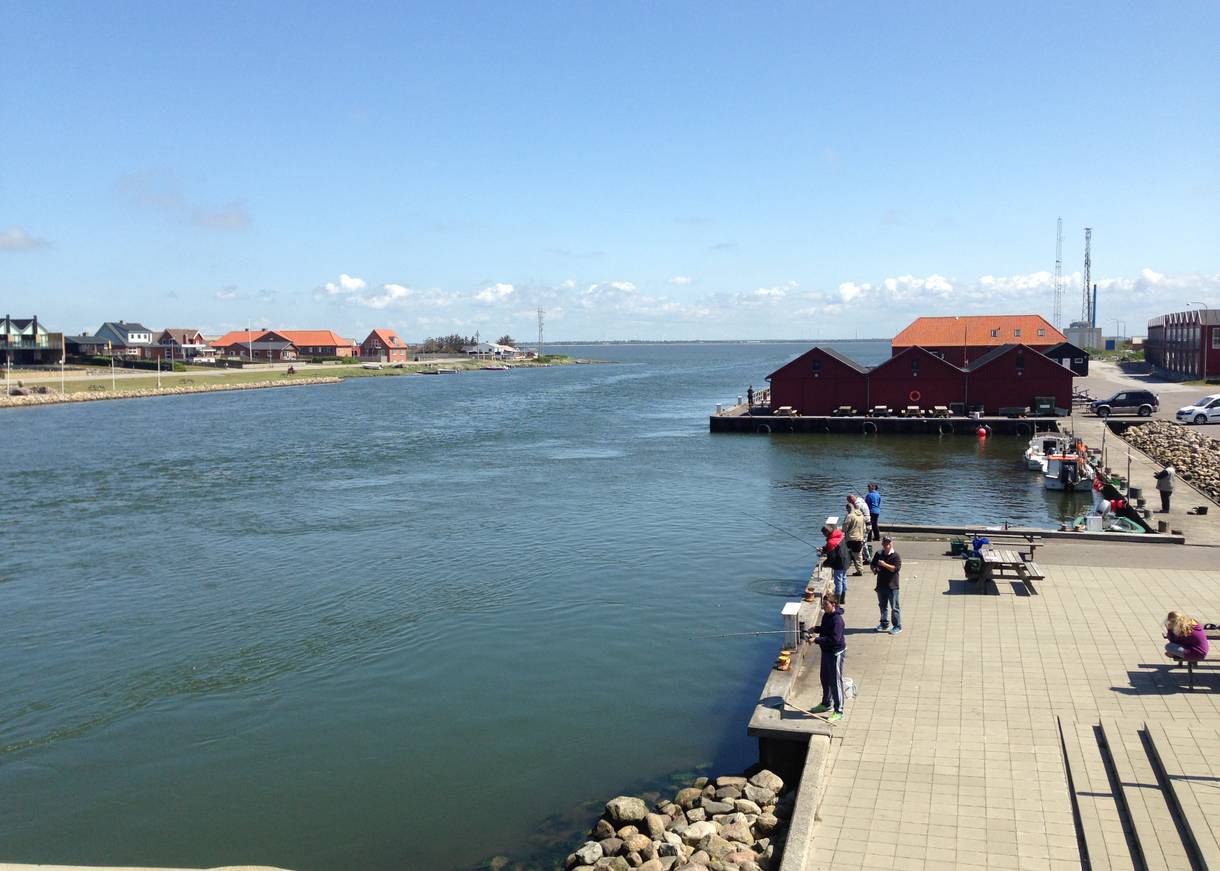 Angler an der Mole einer Schleuse, an beiden Ufern kleine Häuser