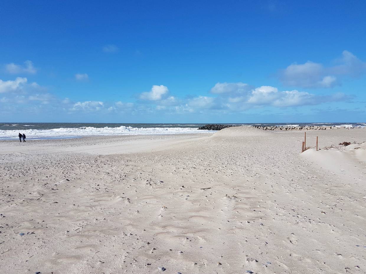 Breiter Sandstrand, in der Ferne Spaziergänger