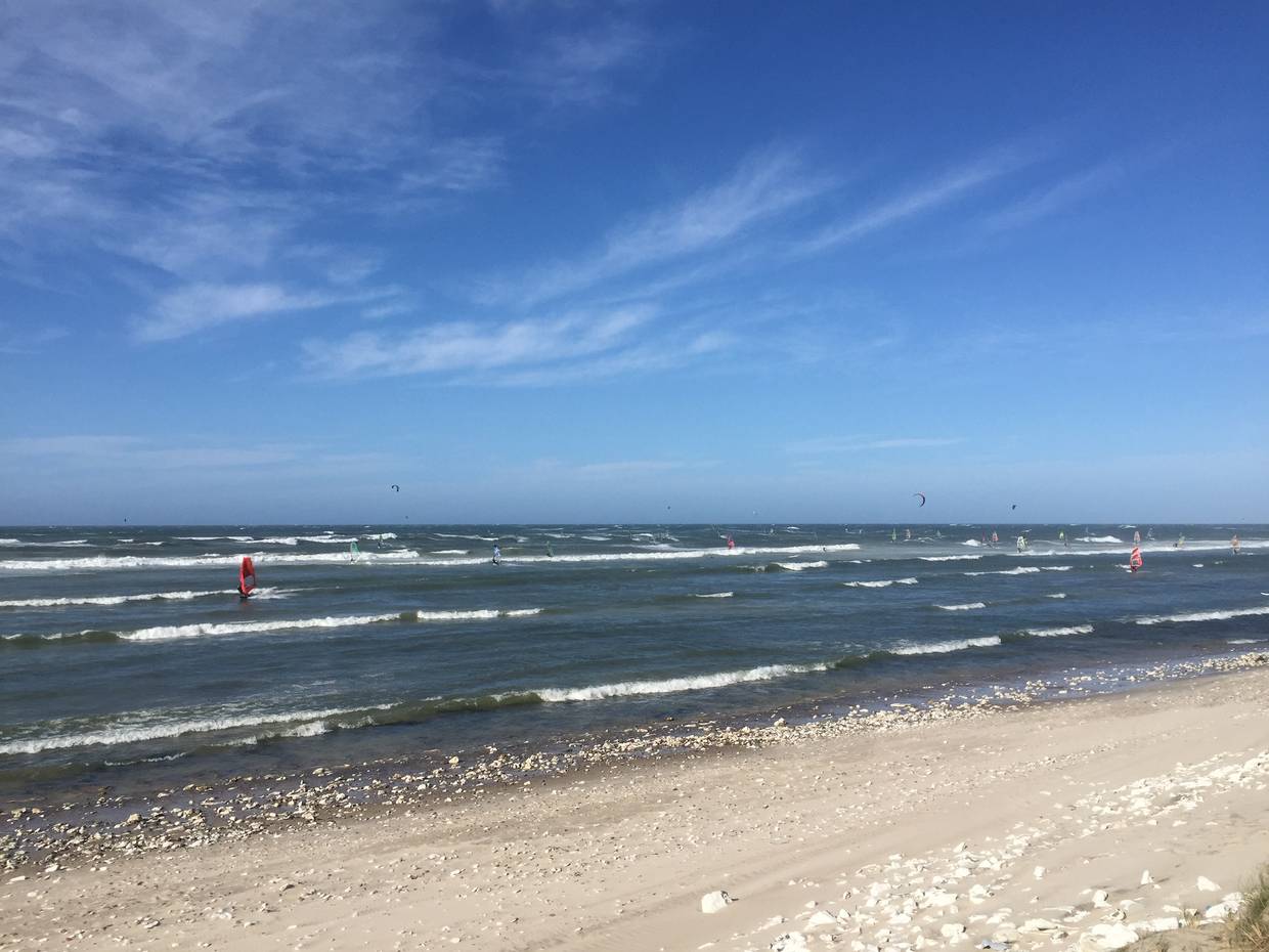 Flache Nordseewellen bei Sonne mit Surfern und Kitern