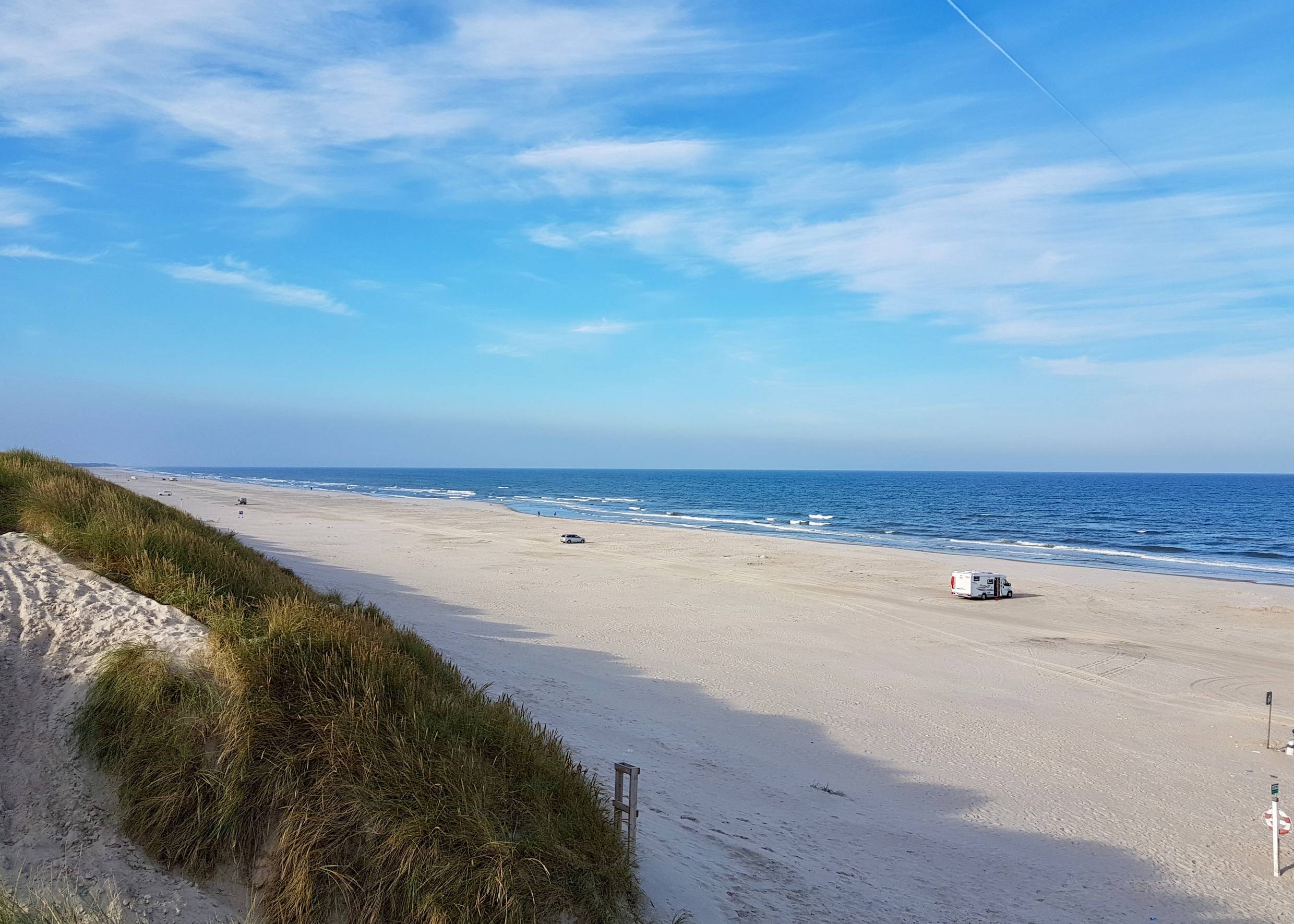 Breiter Sandstrand mit Autos in der Ferne