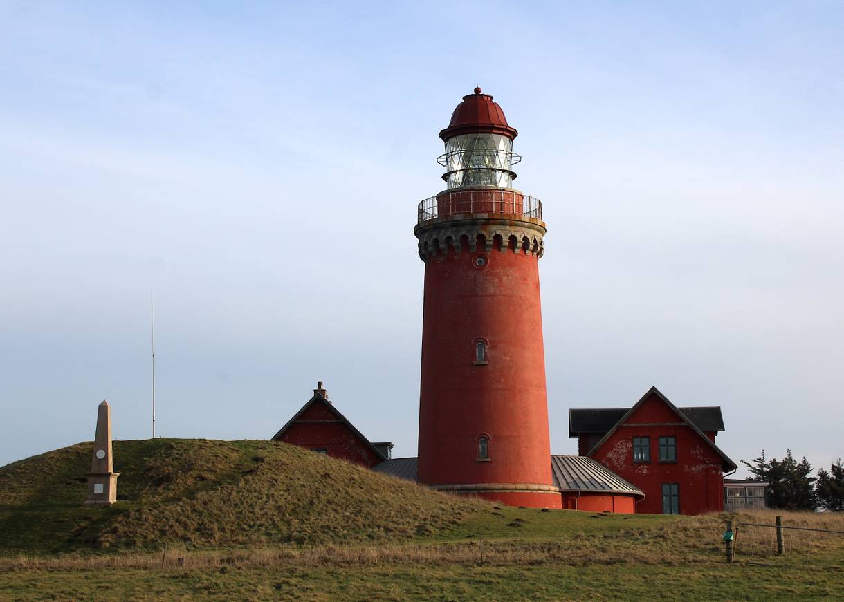 Roter Leuchtturm, danben ein flacher Hügel