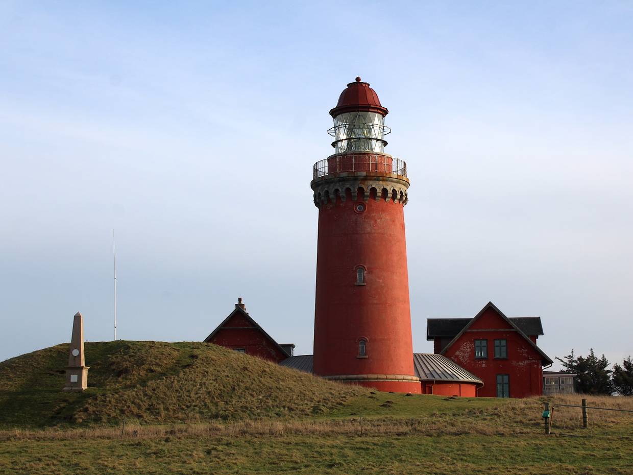 Roter Leuchtturm, danben ein flacher Hügel