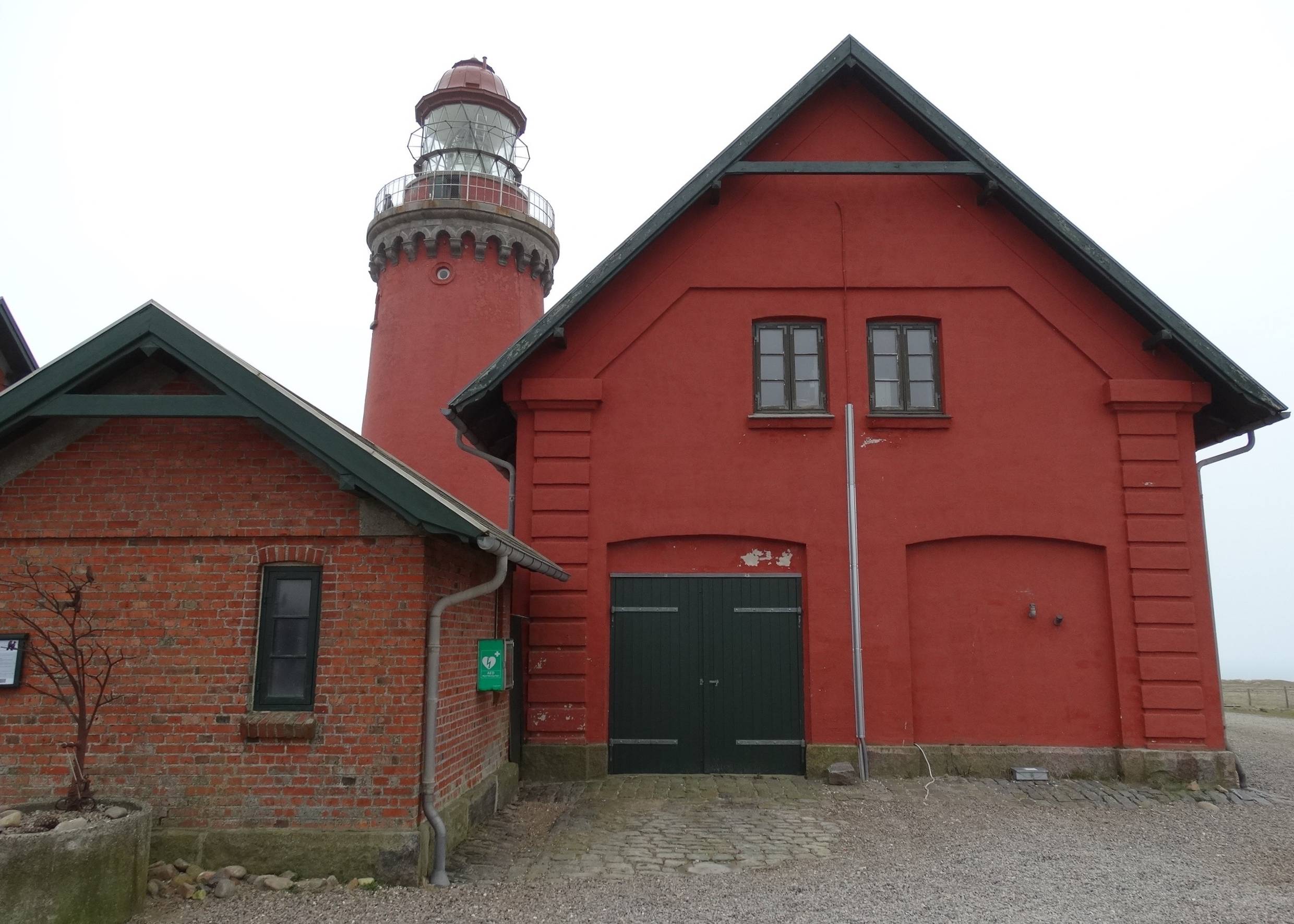 Leuchtturm hinter den roten Nebengebäuden