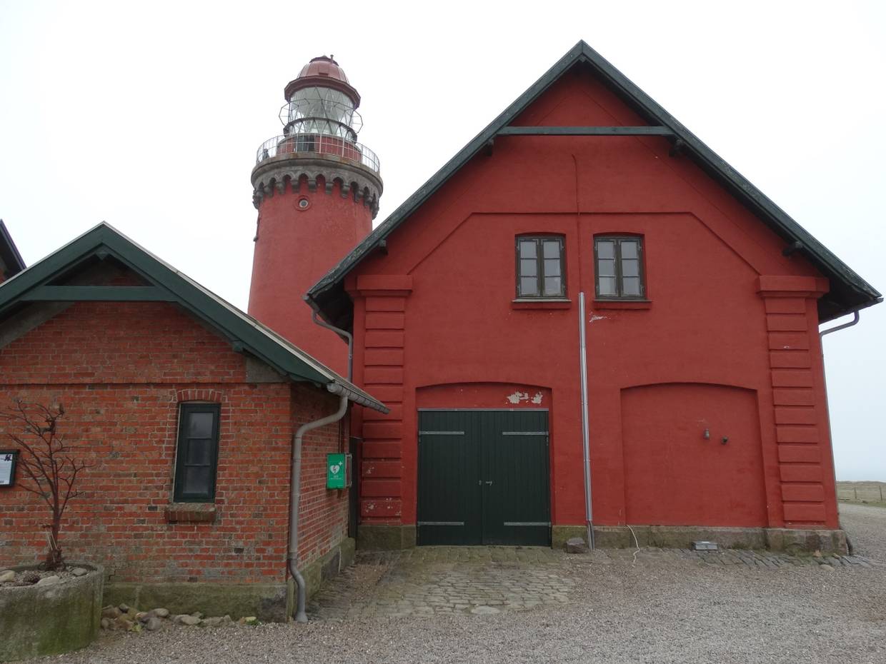 Leuchtturm hinter den roten Nebengebäuden