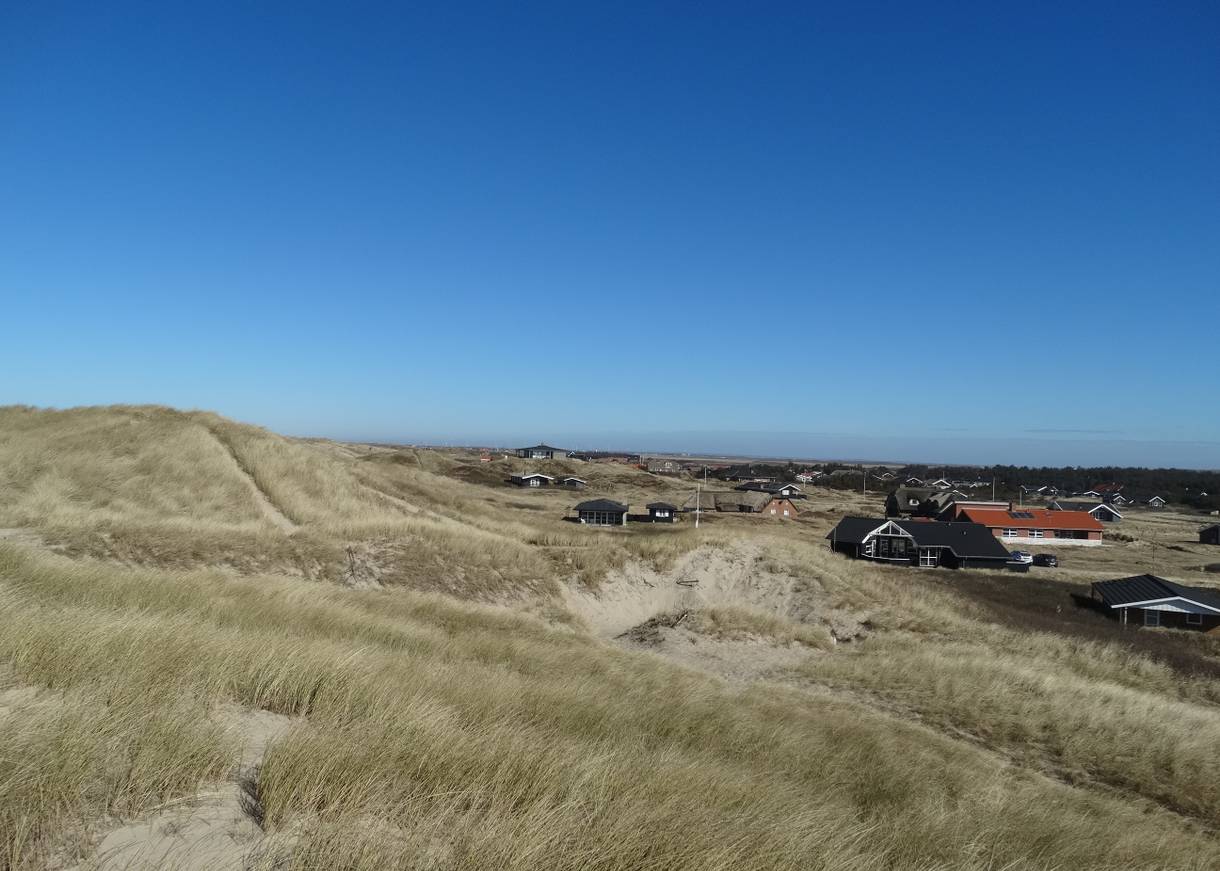 Blick von den Dünen auf Ferienhäuser im Winter, blauer Himmel