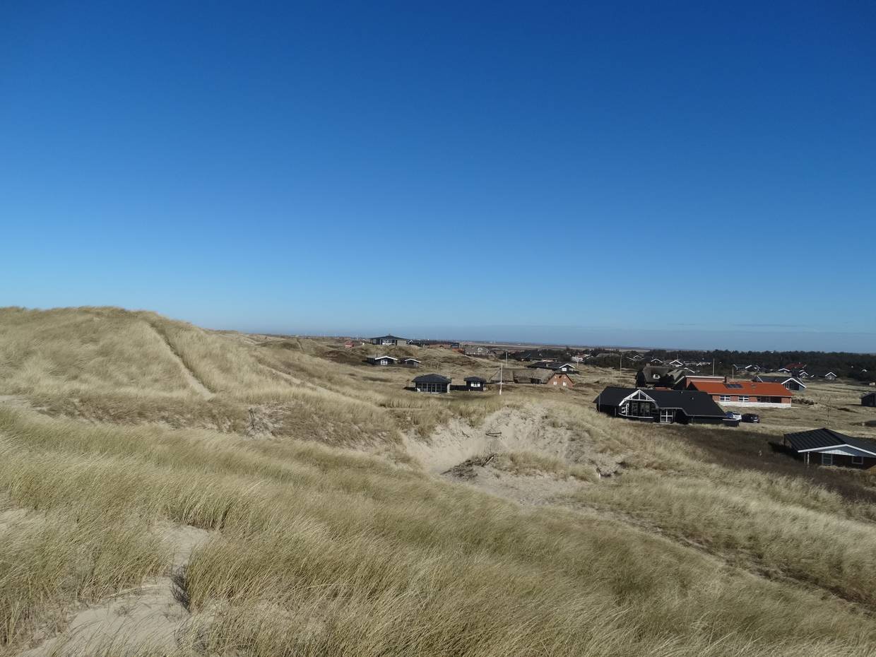 Blick von den Dünen auf Ferienhäuser im Winter, blauer Himmel