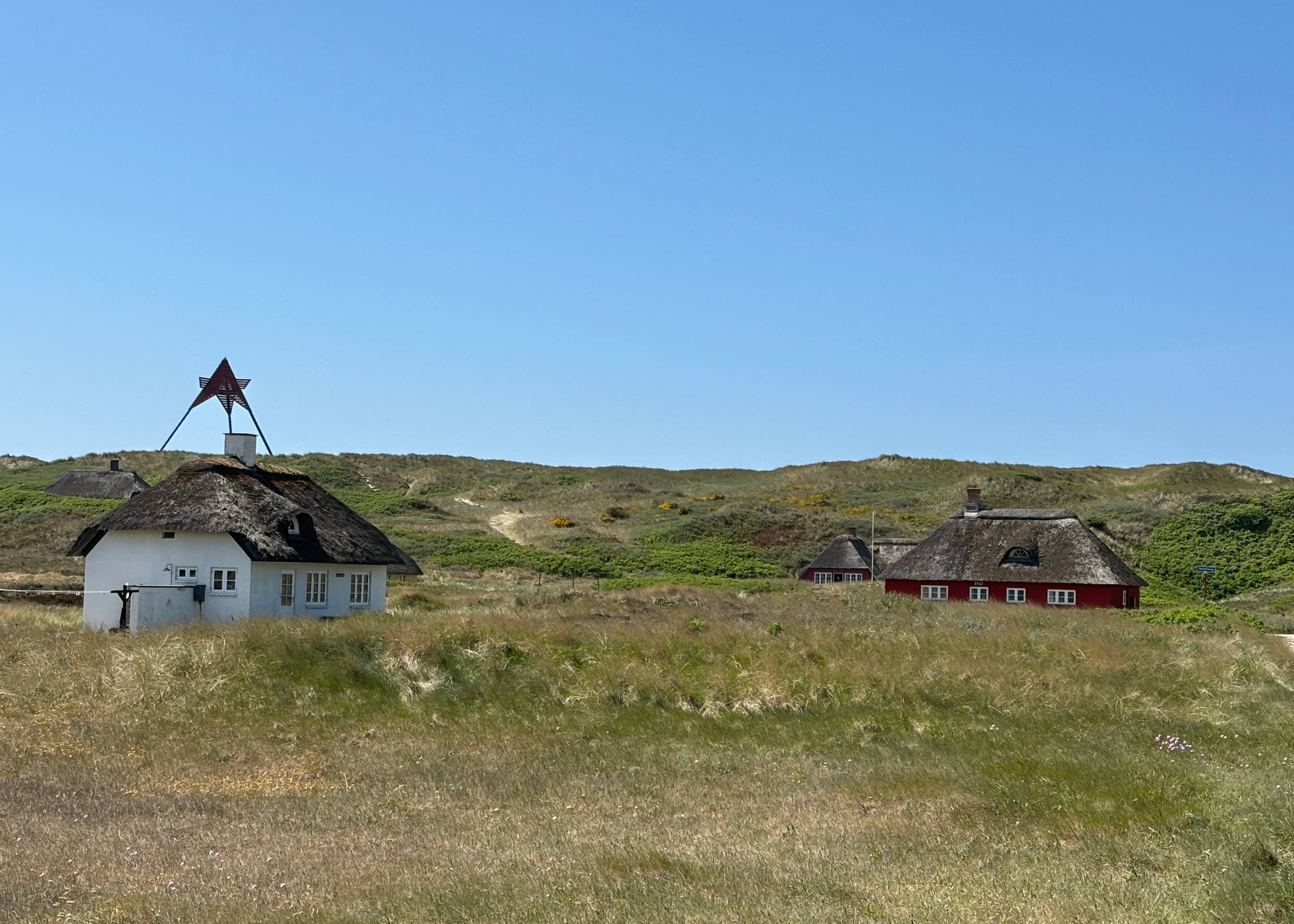 Seezeichen auf den Dünen, davor Ferienhäuser