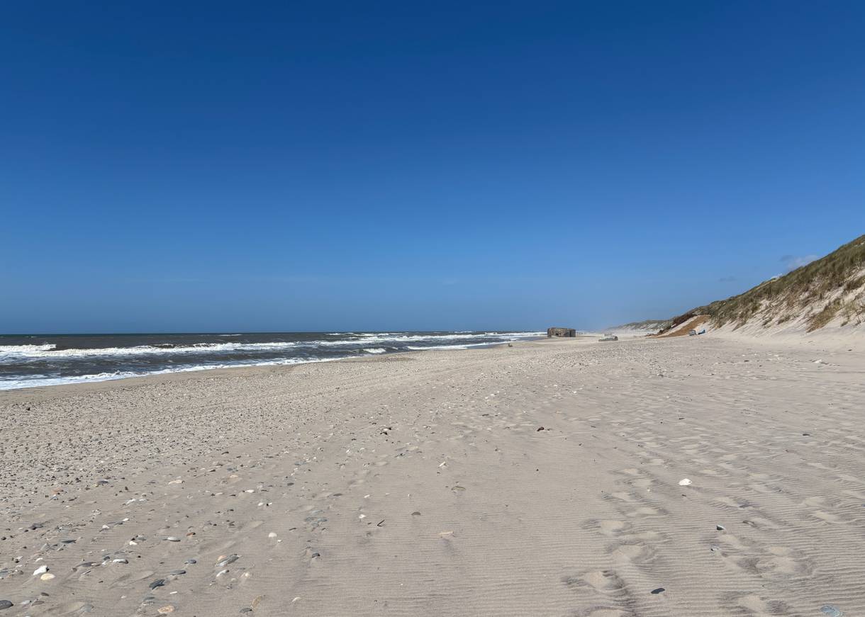 Blick über einen Sandstrand mit einem Bunker
