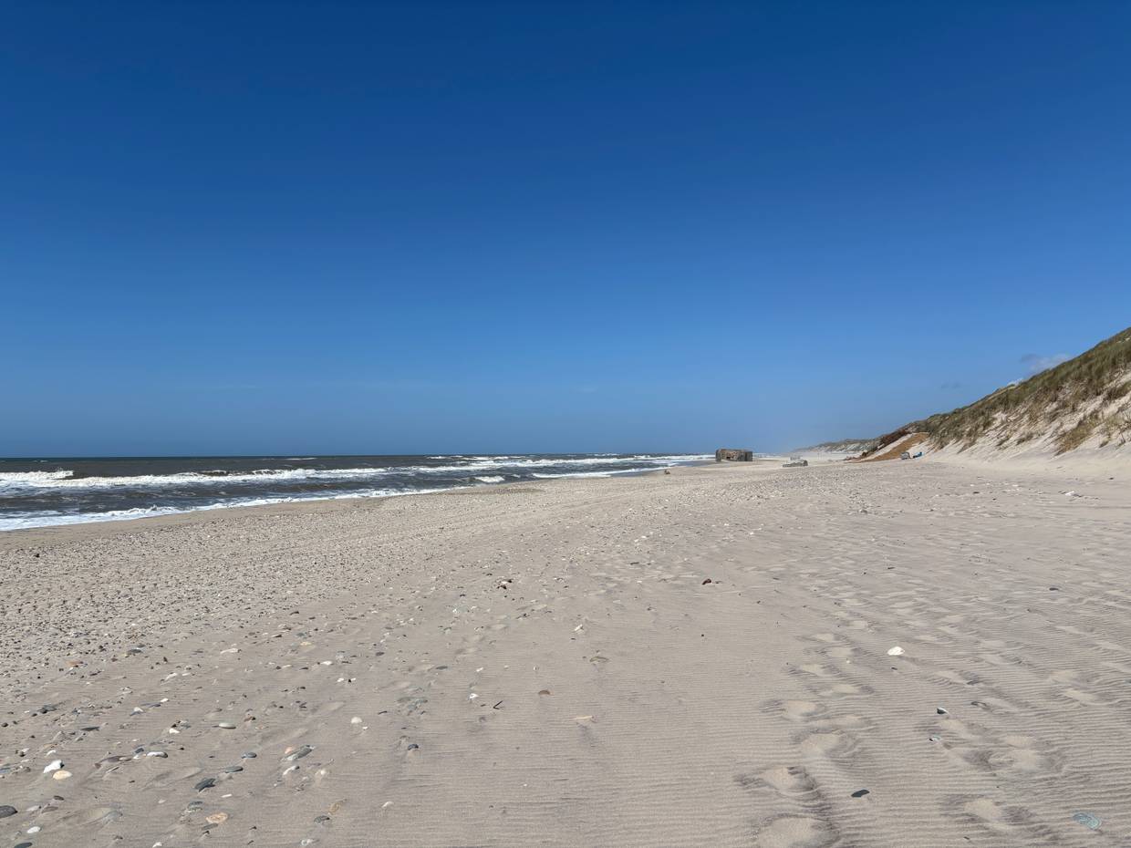 Blick über einen Sandstrand mit einem Bunker