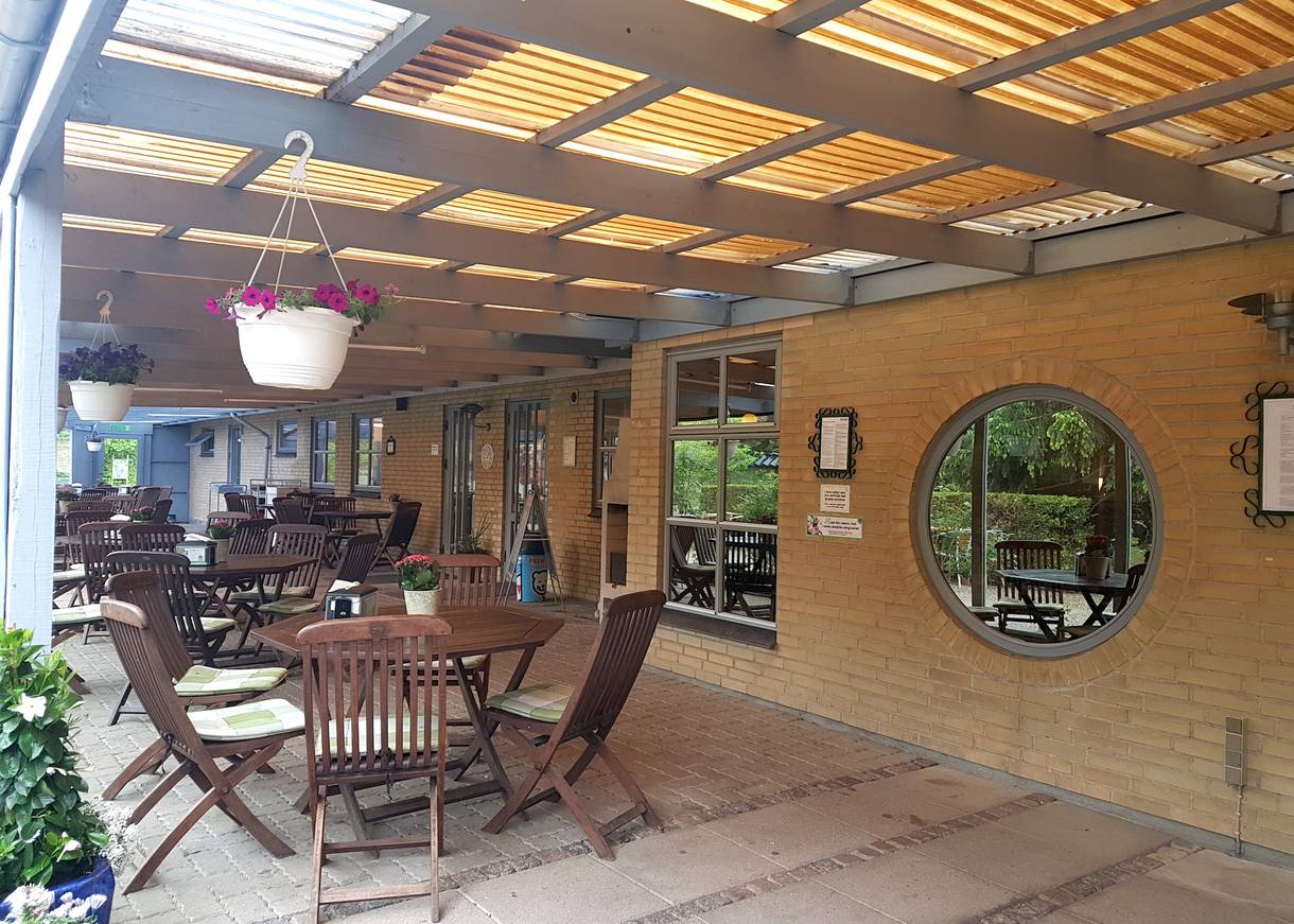 Überdachte Gastterrasse mit vielen Holzgartenmöbeln