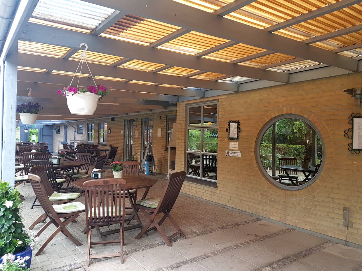 Überdachte Gastterrasse mit vielen Holzgartenmöbeln