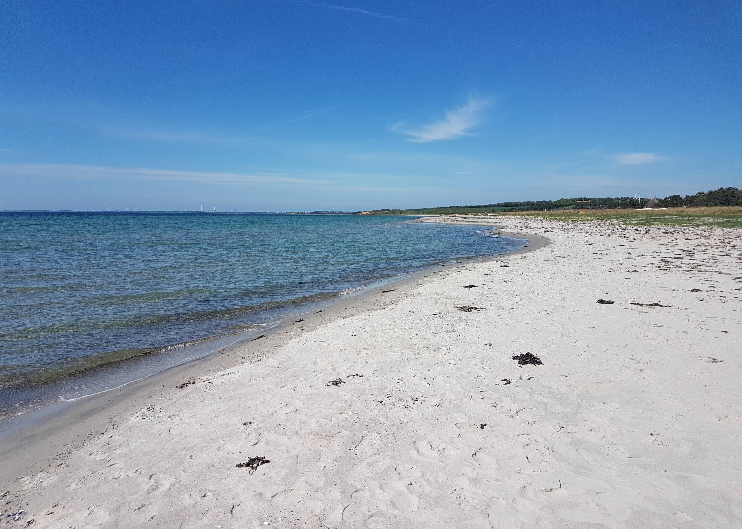 Blick über einen weißen Sandstrand unter blauem Himmel 