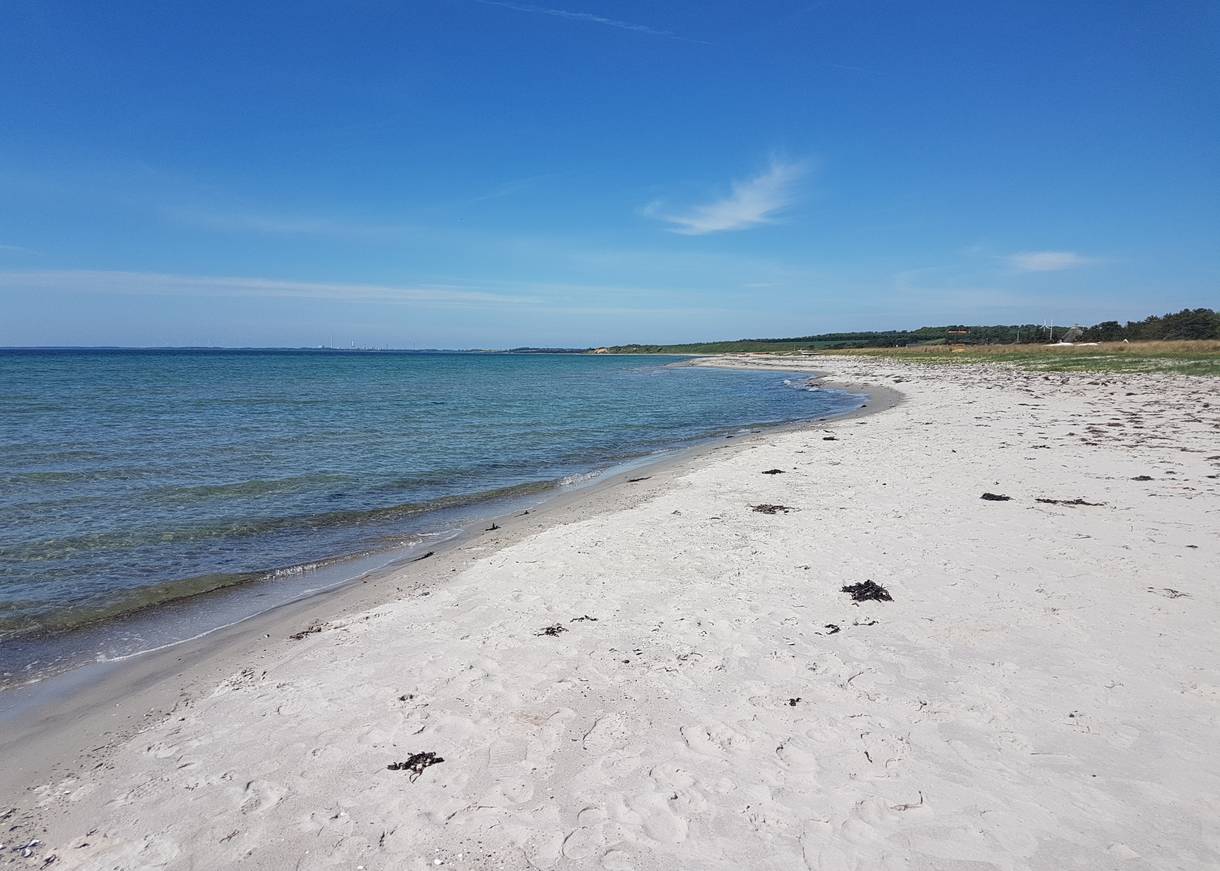 Blick über einen weißen Sandstrand unter blauem Himmel 