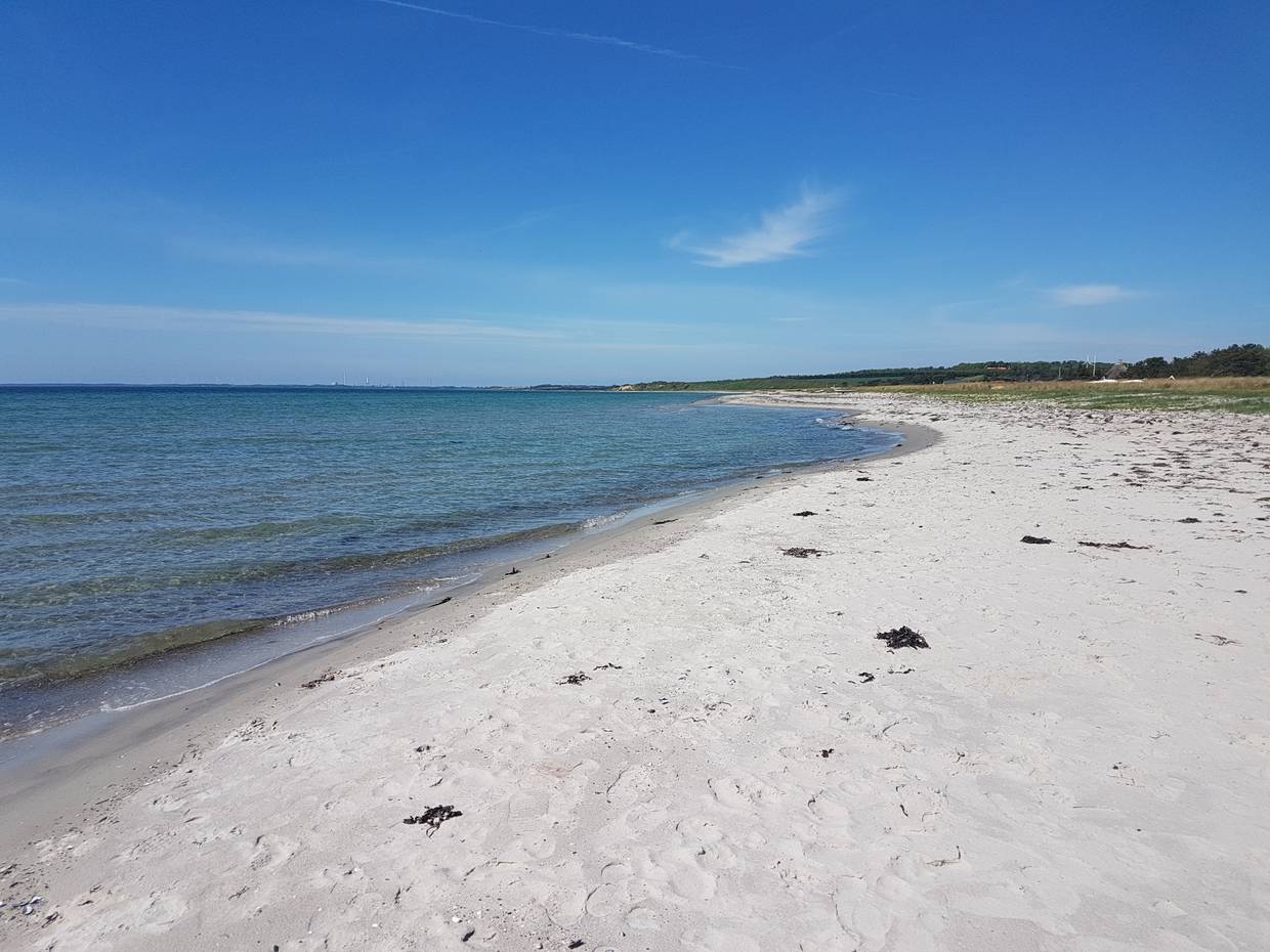 Blick über einen weißen Sandstrand unter blauem Himmel 