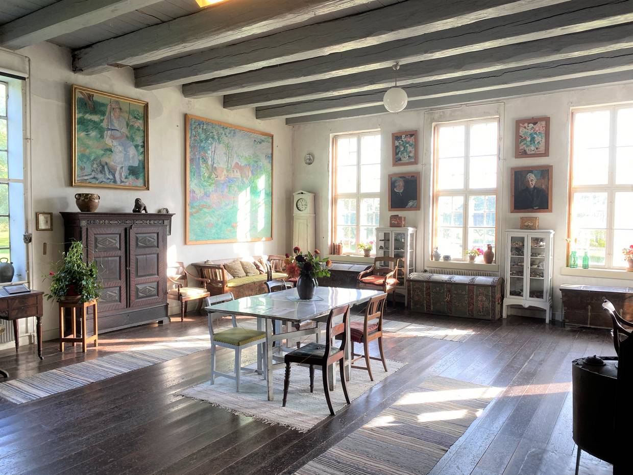Helles Zimmer mit dunklen Holzmöbeln und großen Fenstern