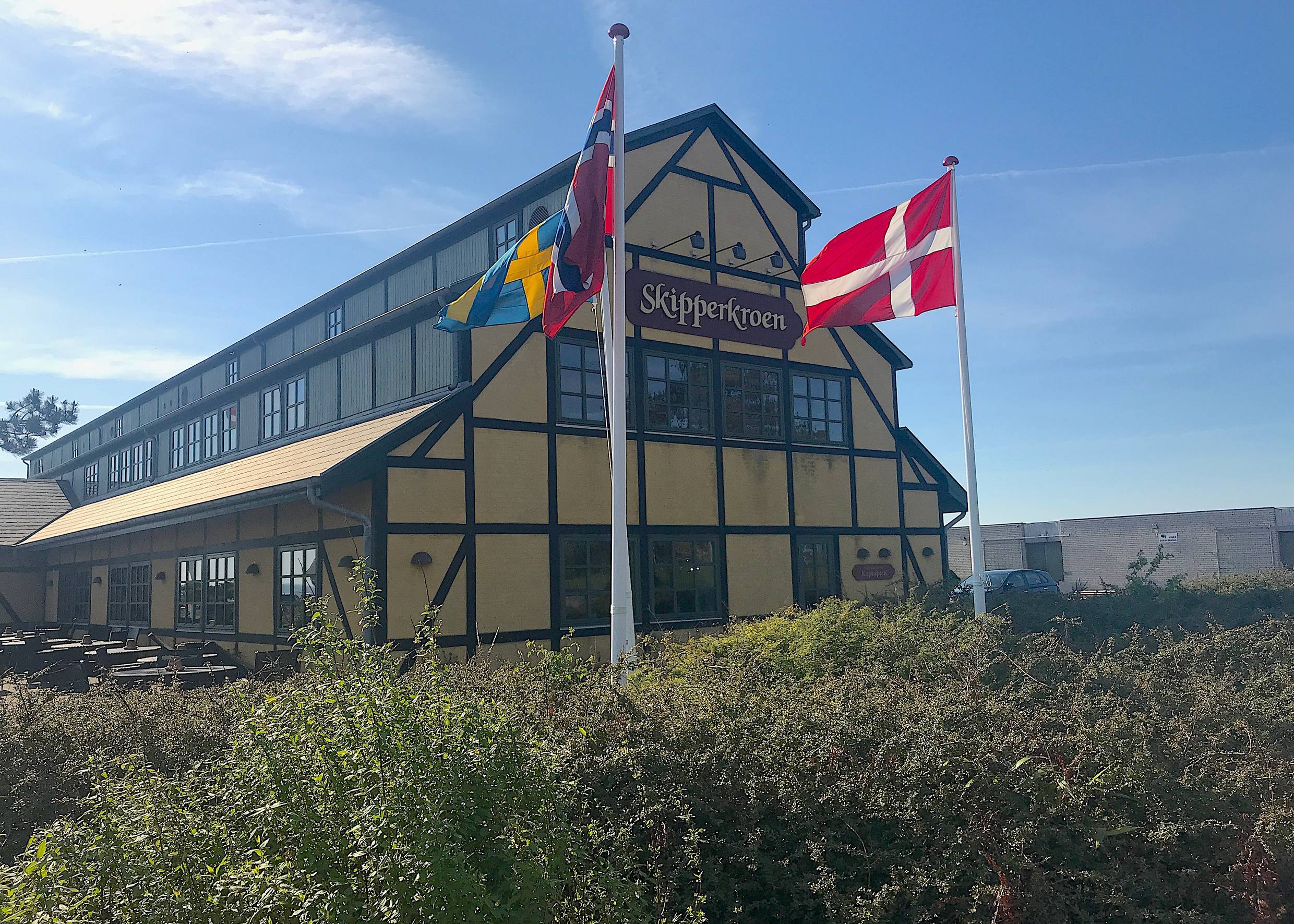 Gelb-schwarzes großes Hotel im Fachwerkstil, dafür Fahnen im Wind