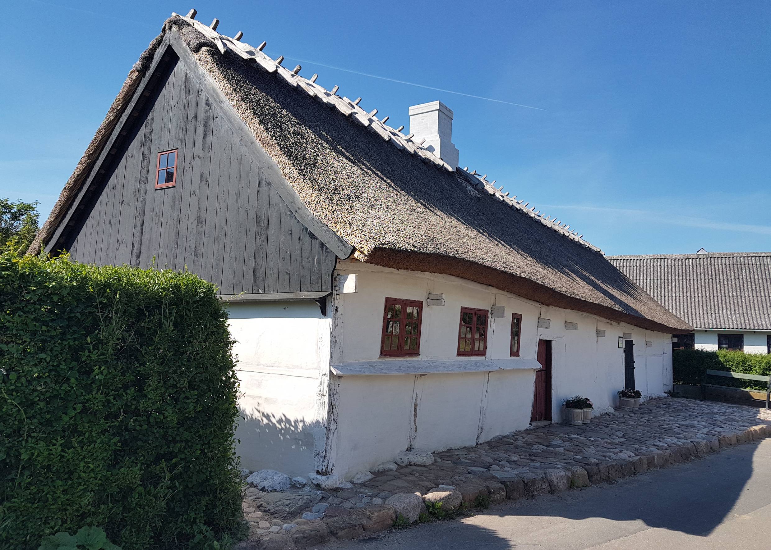 Schlichtes, kleines, weiß getünchtes Reetdachhaus