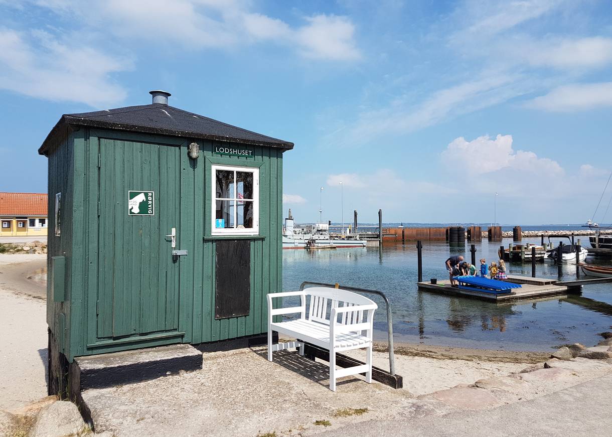 Grünes Lotsenhaus am Hafen, dahinter Restaurantterrassen