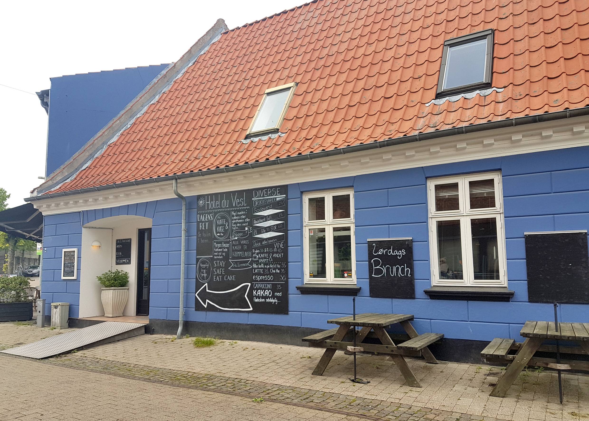 Blaues Haus mit hangemalten Hinweisschildern auf das gastronomische Angebot