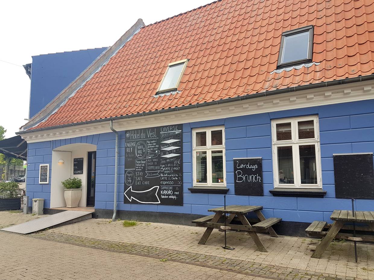 Blaues Haus mit hangemalten Hinweisschildern auf das gastronomische Angebot