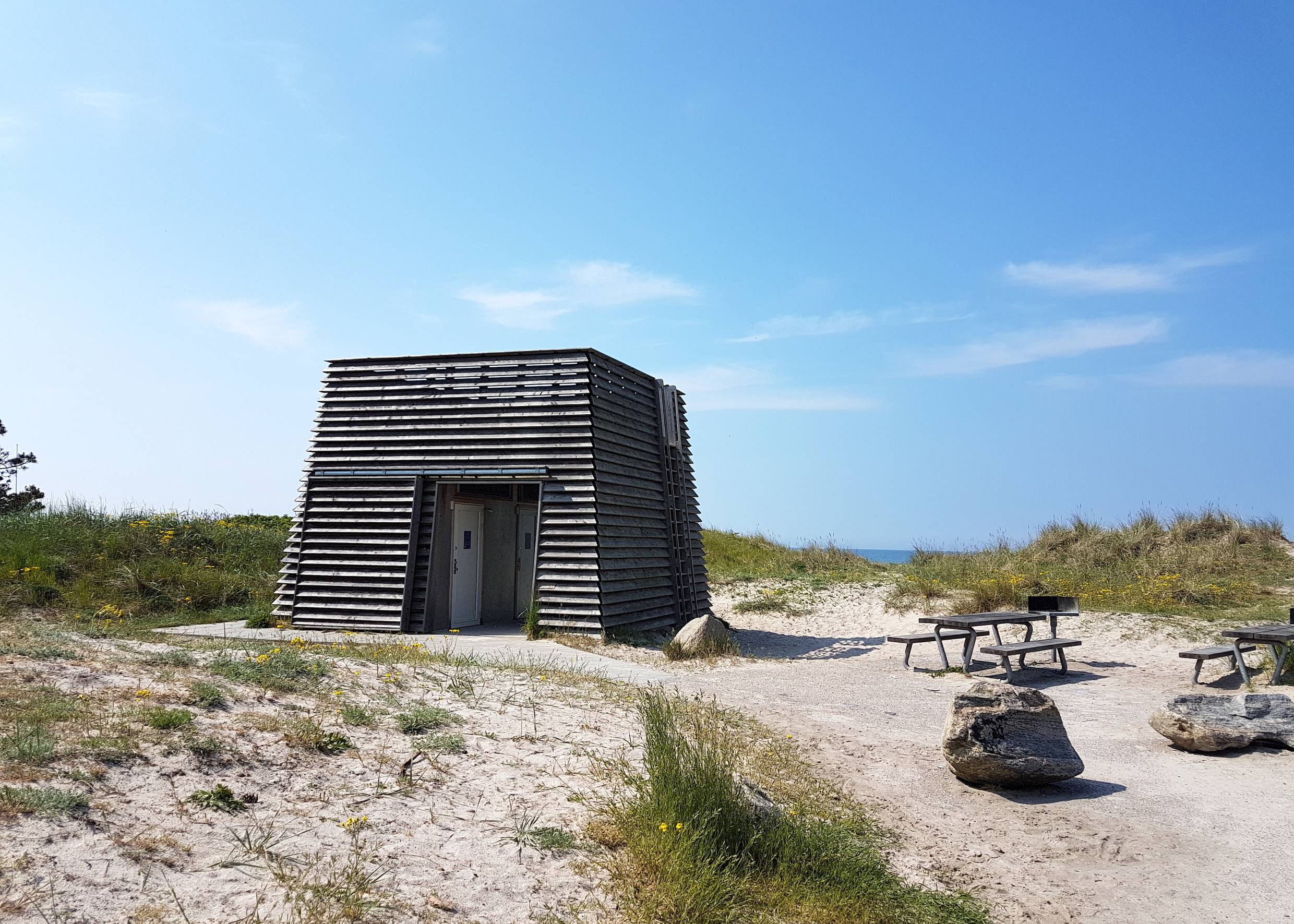 Viereckiger Holzturm, davor Picknickbänke am Rørvig Strand