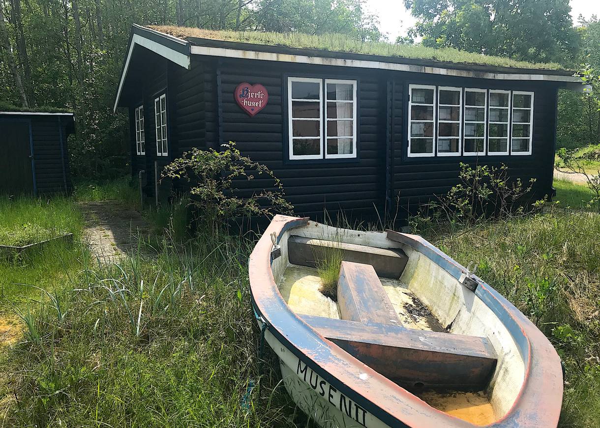 Schwarzes Holzferienhaus, davor ein altes Ruderboot