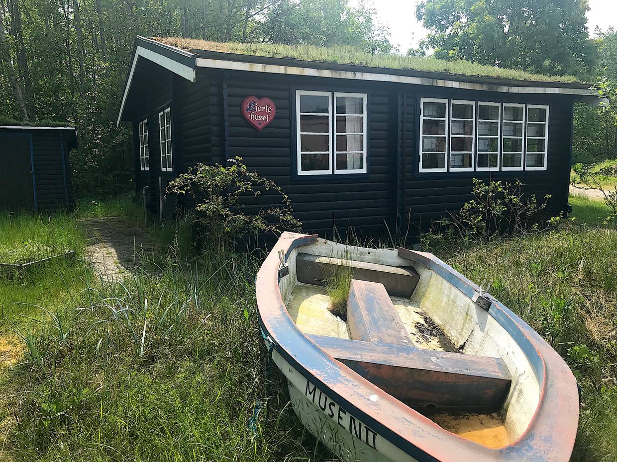 Schwarzes Holzferienhaus, davor ein altes Ruderboot