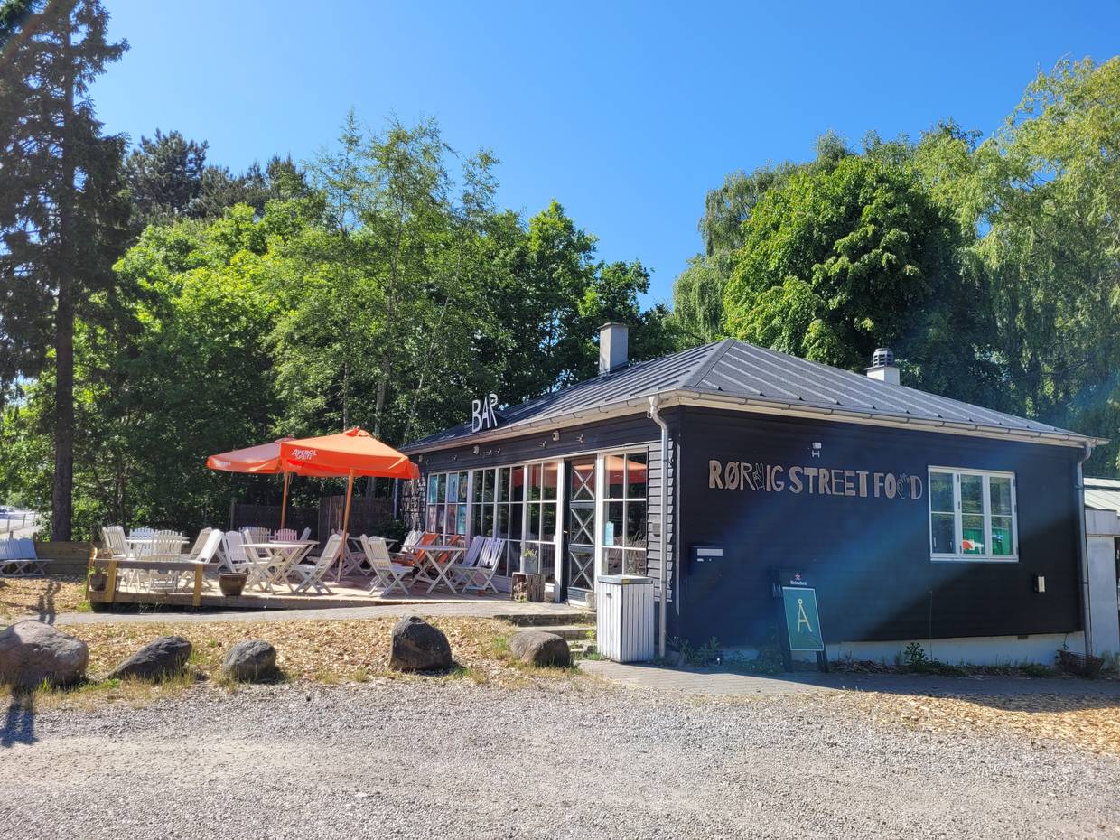 Bistro mit Außensitzplätzen vor einem Waldstück