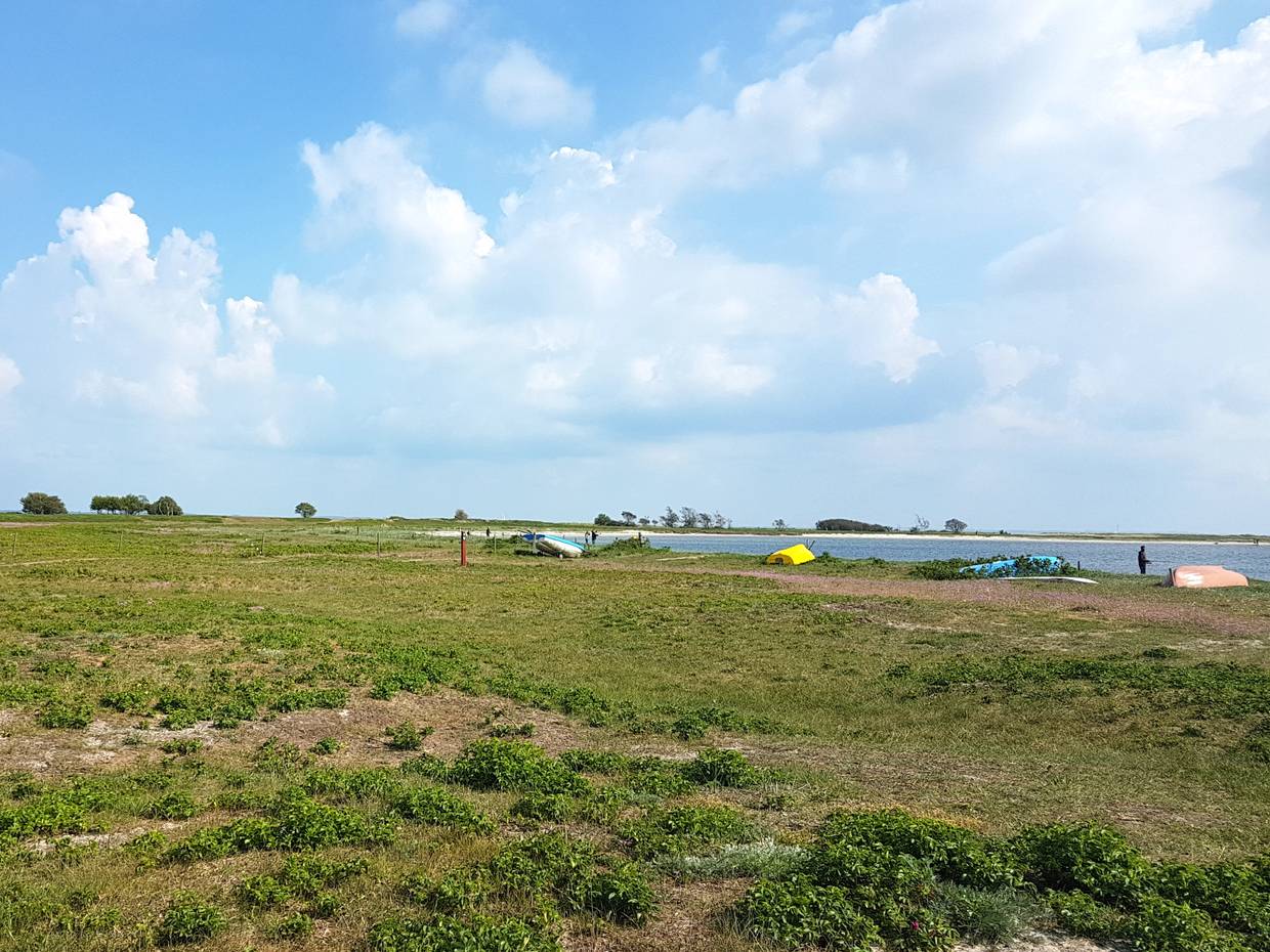 Runde Bucht mit Booten auf der wiese und Anglern am Strand