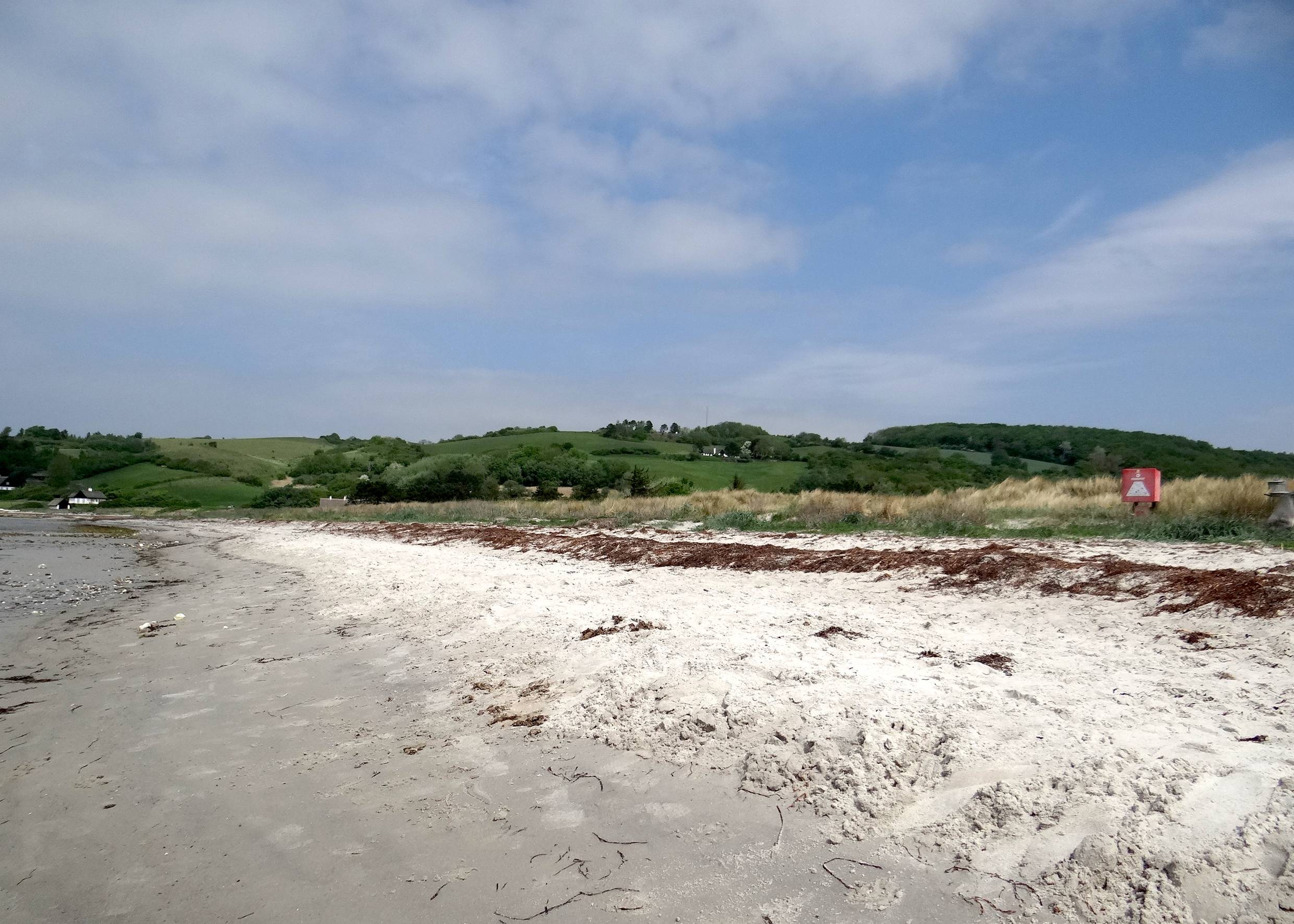 Strand, im Hingtergrund grüne Hügel