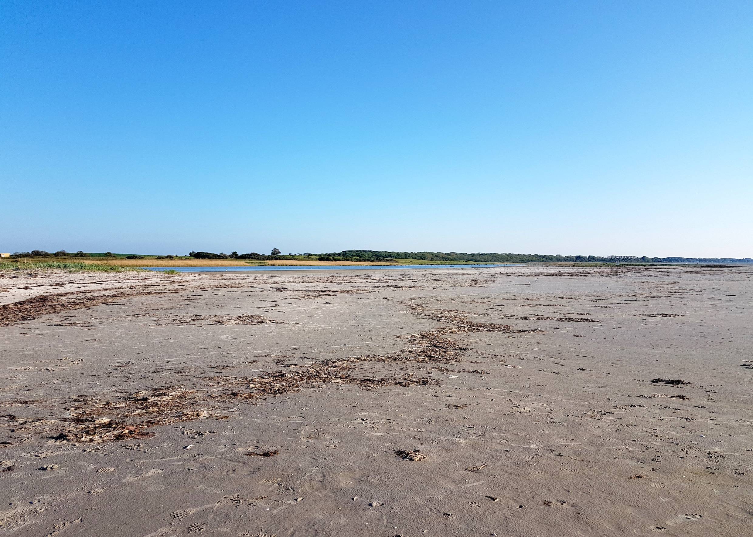 Sehr breiter, flacher Sand, im Hintergrund eine Lagune