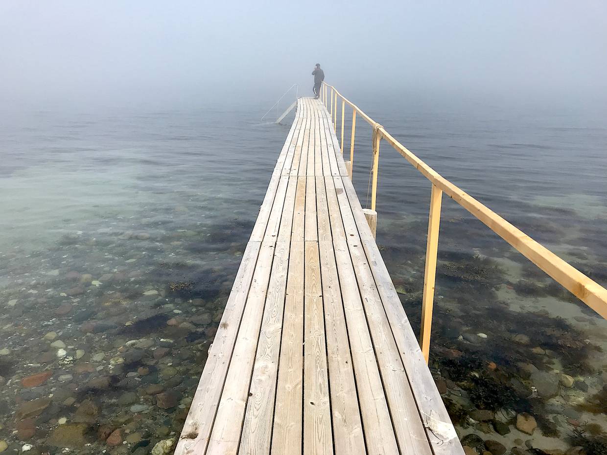 Hölzerner Badesteg ins Meer am steinigen Strand